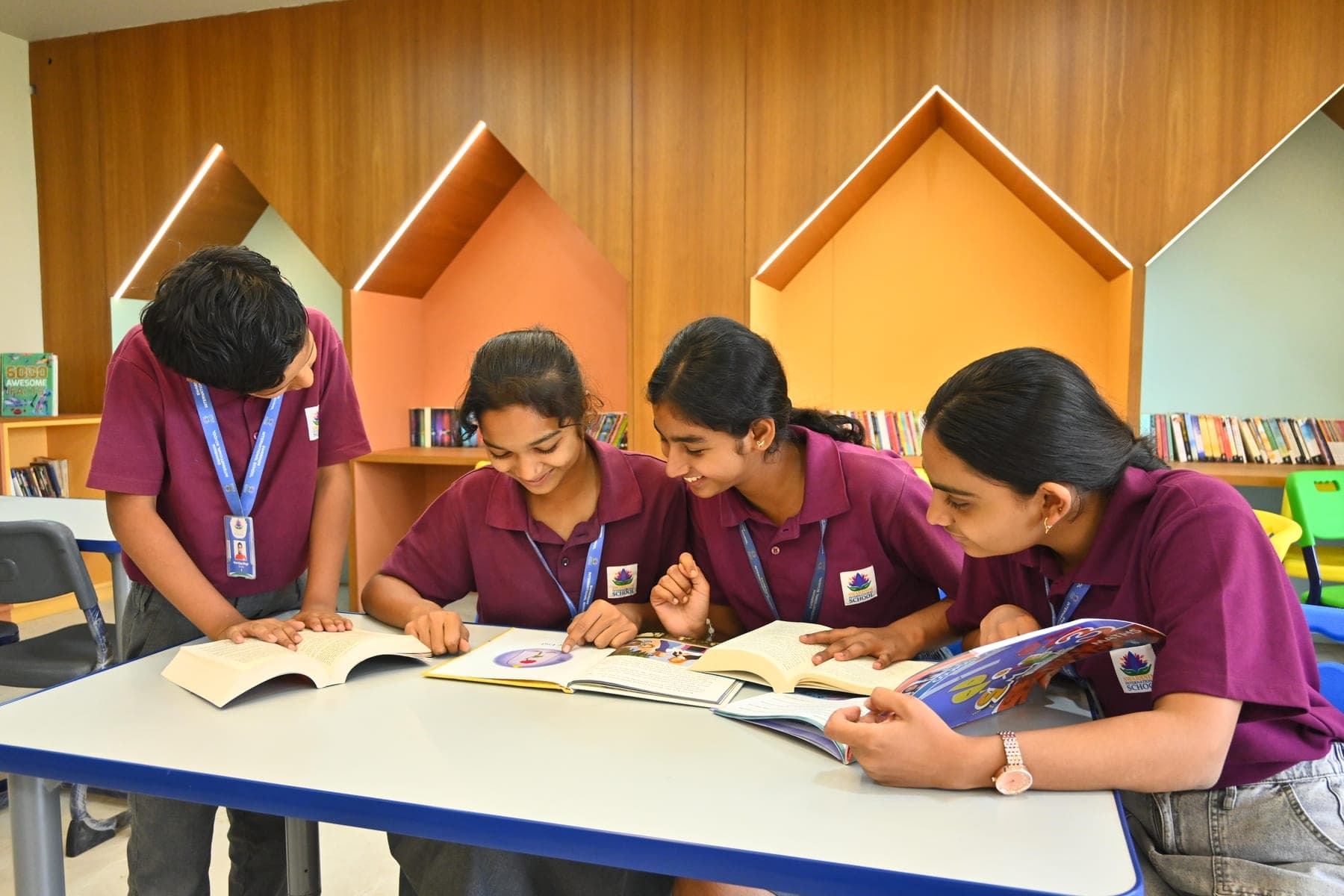 Four students reading books together at a table in the school library