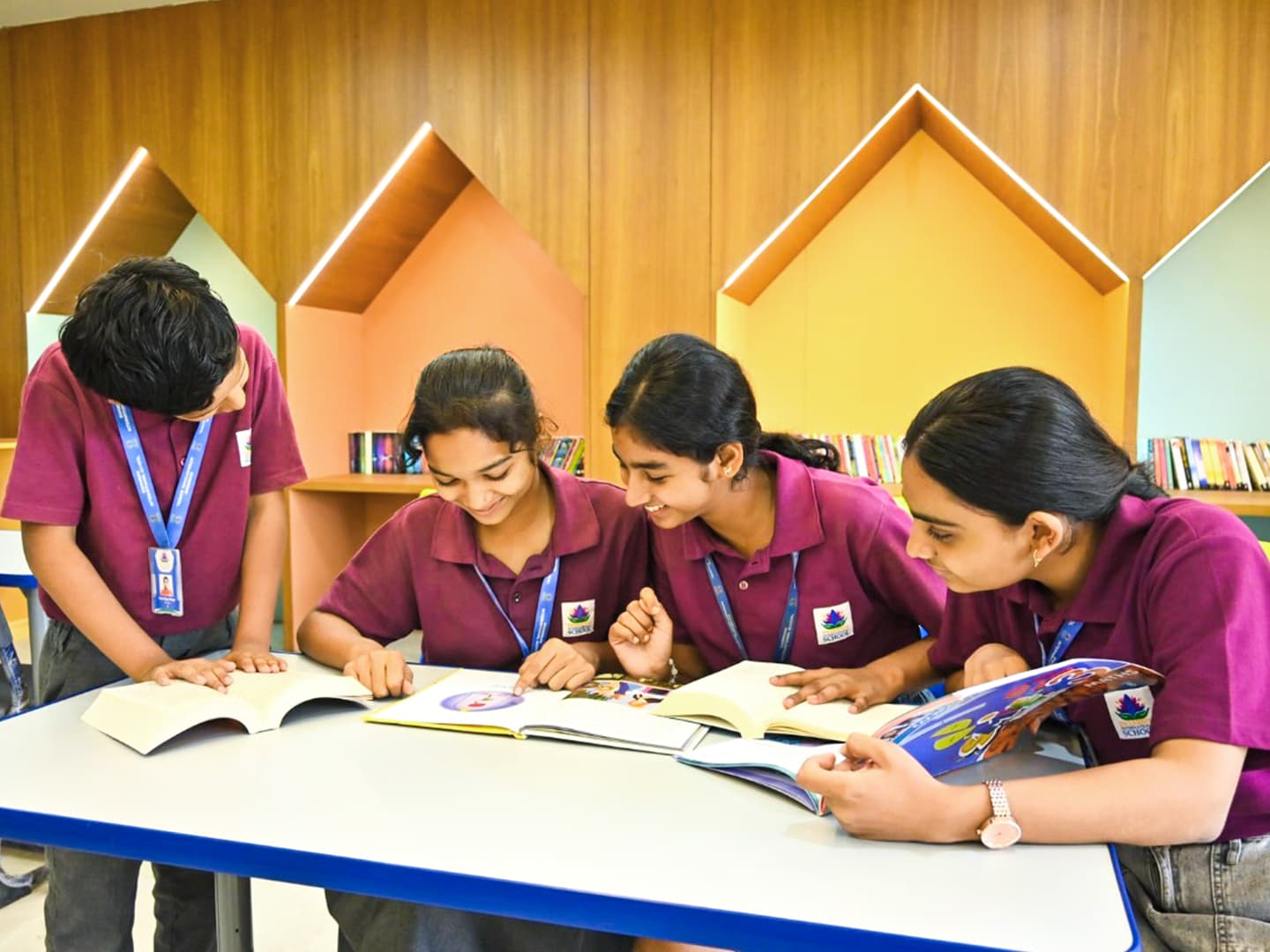 Four students reading books together at a table in the school library