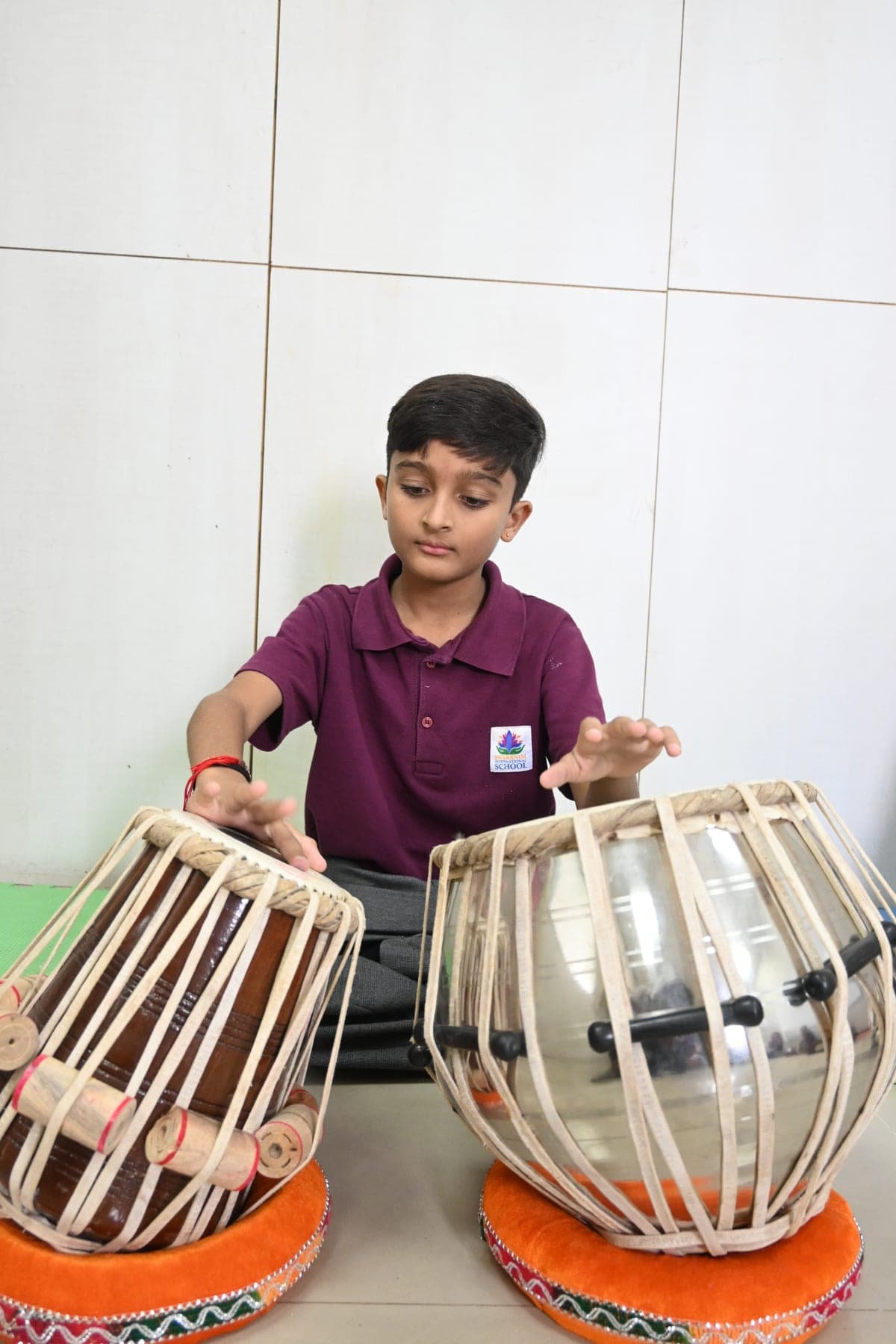 A student playing a pair of tabla drums during a music lesson