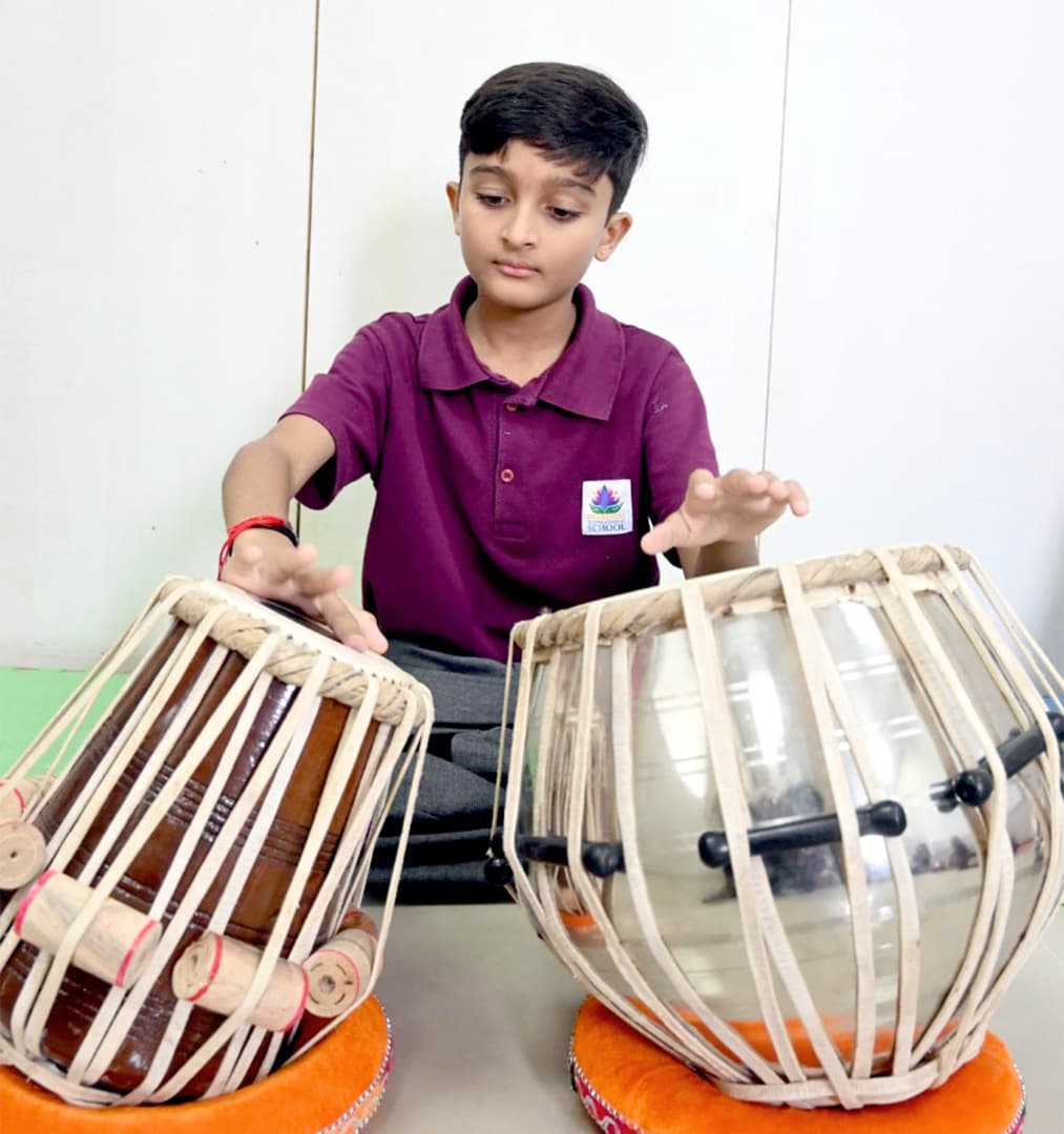 A student playing a pair of tabla drums during a music lesson