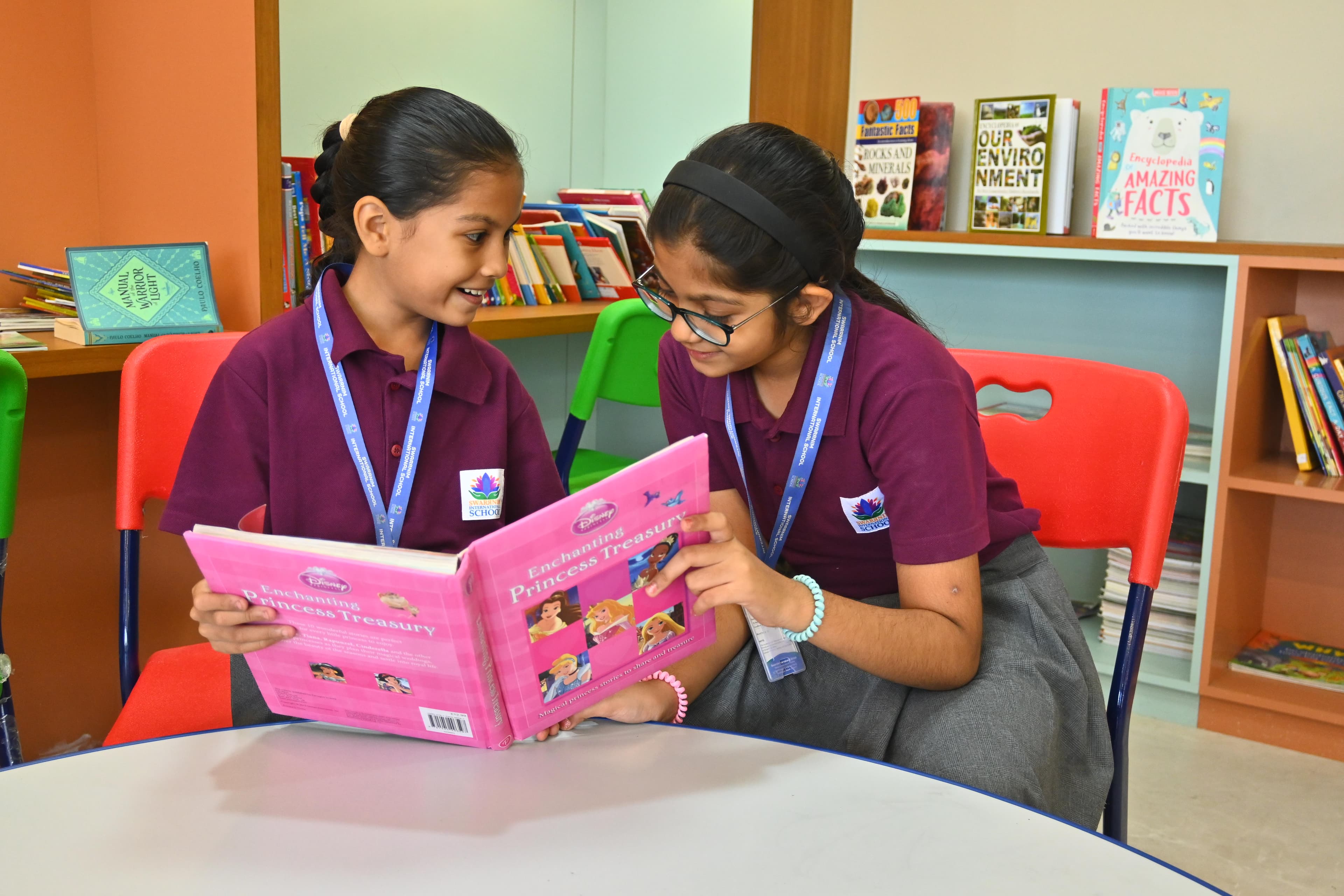 Two girls happily sharing a Disney storybook together at the library