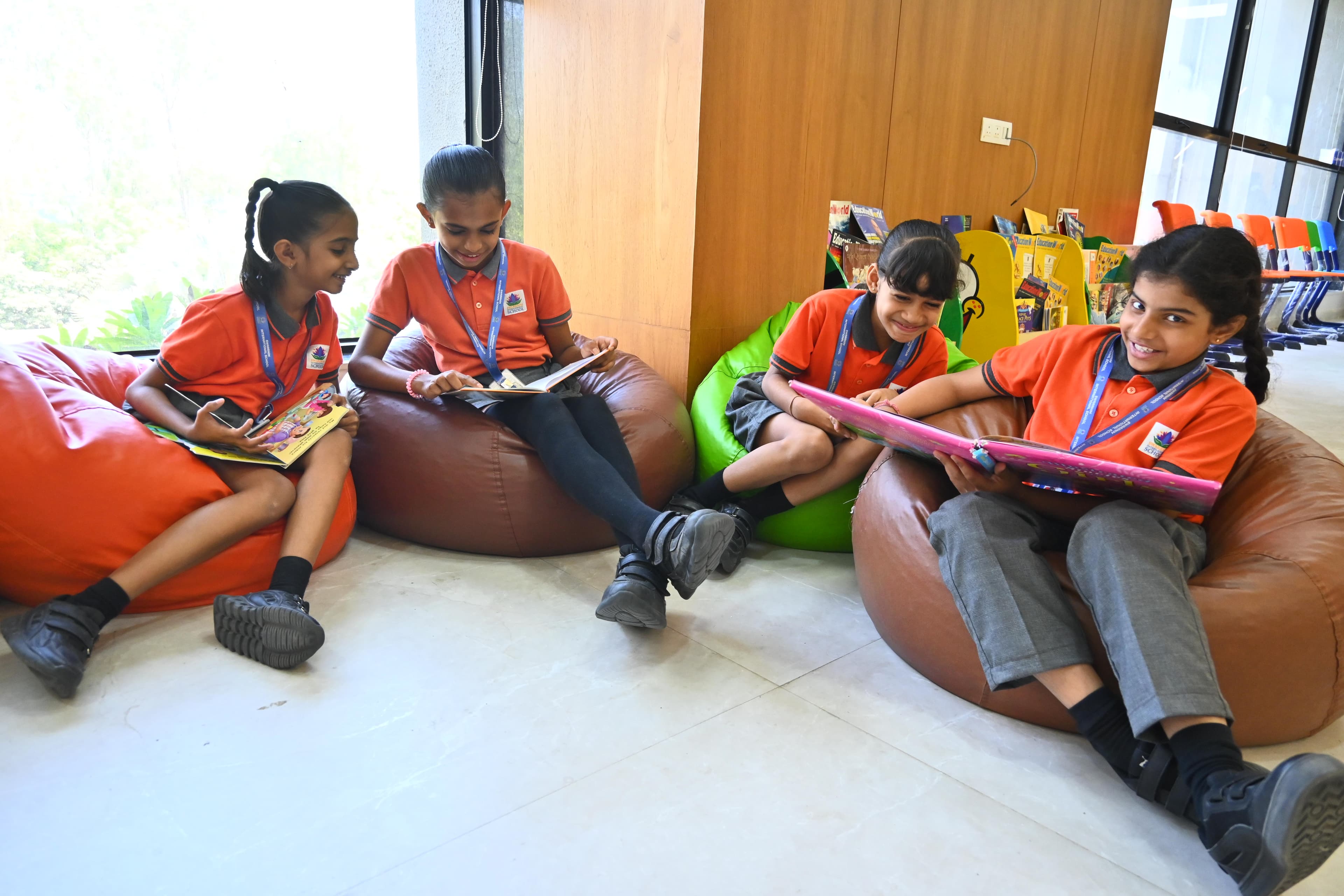 Four primary students happily reading on colourful bean bags in the reading nook