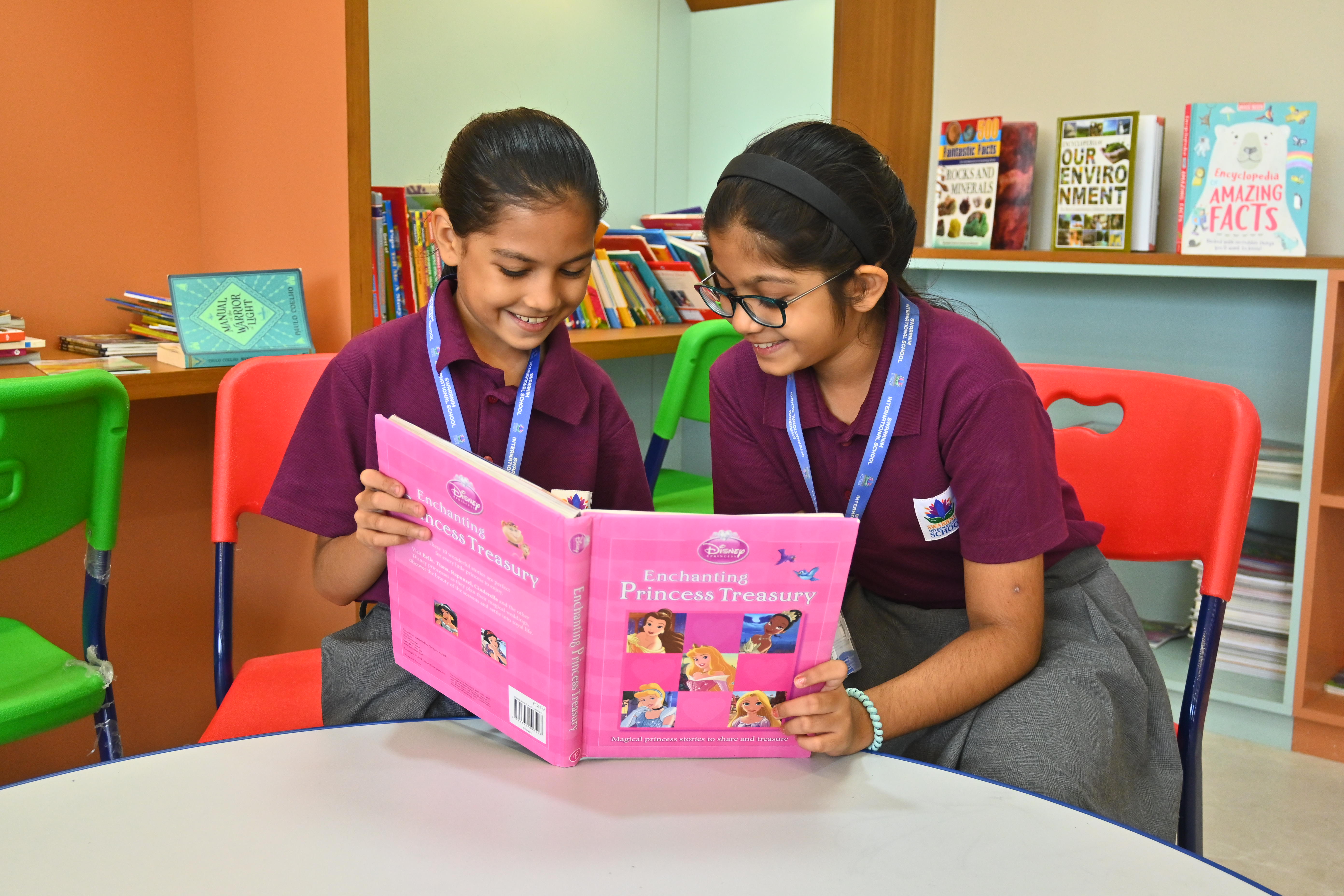 Two students reading a picture book together in the school library